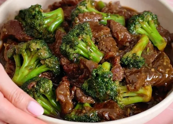 Beef and broccoli stir-fry served in a bowl with chopsticks.