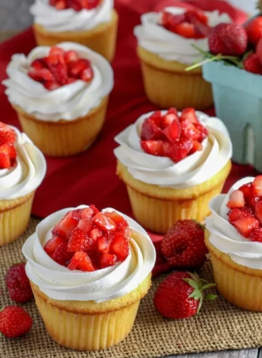 Strawberry shortcake cupcakes topped with fresh cream and strawberries