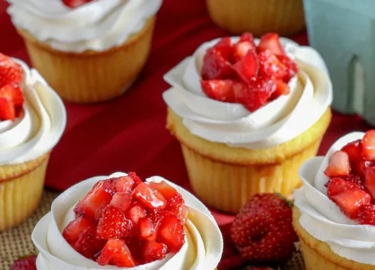 Strawberry shortcake cupcakes topped with fresh cream and strawberries