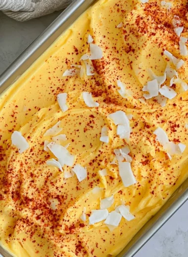 Chili Lime Mango Sorbet served in a bowl with fresh mango slices and lime wedges.