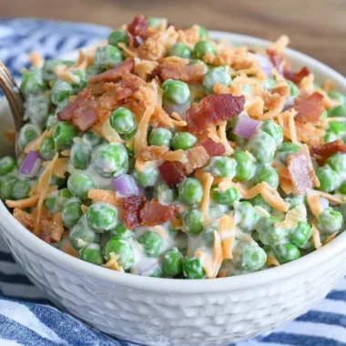 Classic pea salad with bacon served in a bowl, garnished with fresh herbs.