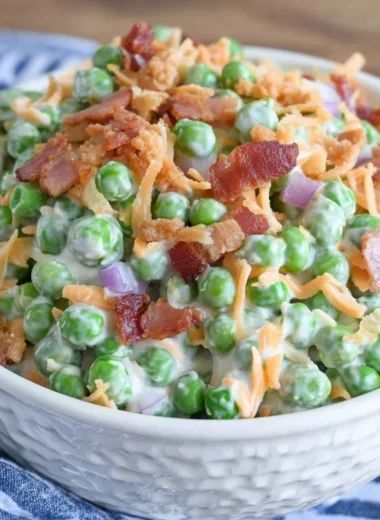 Classic pea salad with bacon served in a bowl, garnished with fresh herbs.