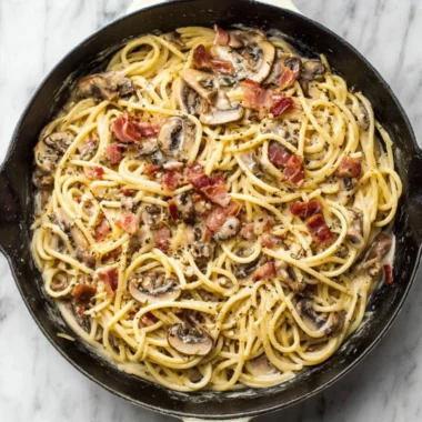 Creamy bacon mushroom pasta served in a bowl with herbs on top