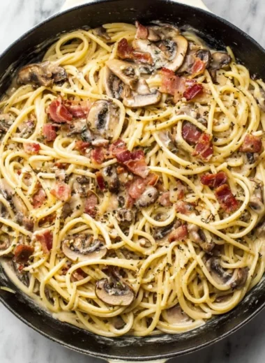Creamy bacon mushroom pasta served in a bowl with herbs on top