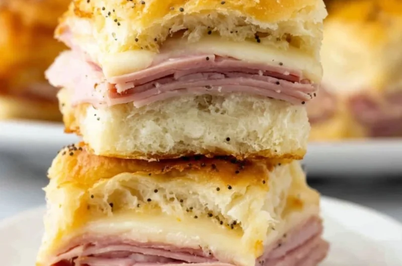 Ham and cheese sliders stacked on a serving platter, ready to be enjoyed.