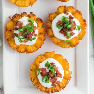 Plate of loaded tater tots topped with cheese, bacon, and green onions.