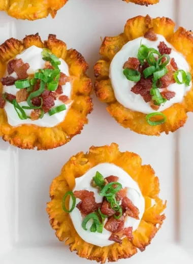 Plate of loaded tater tots topped with cheese, bacon, and green onions.