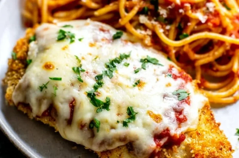 Oven baked chicken parmesan served with pasta and fresh herbs