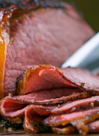 A succulent smoked roast beef on a wooden cutting board, garnished with herbs.