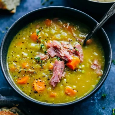 Bowl of homemade split pea soup garnished with herbs and bread