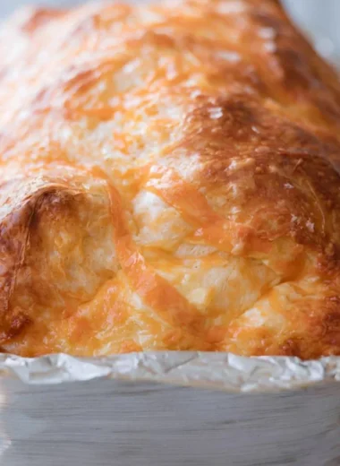 Warm and cheesy sourdough cheese bread loaf on a rustic wooden table