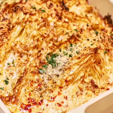 Creamy garlic butter cabbage dish garnished with herbs.