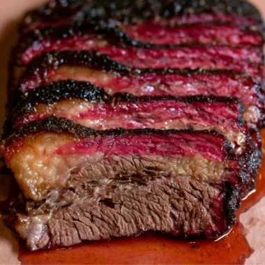 Smoked beef chuck roast served on a wooden cutting board with herbs.