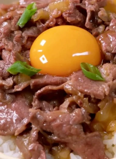 Delicious Cozy Gyudon Japanese beef bowl topped with scallions and egg.